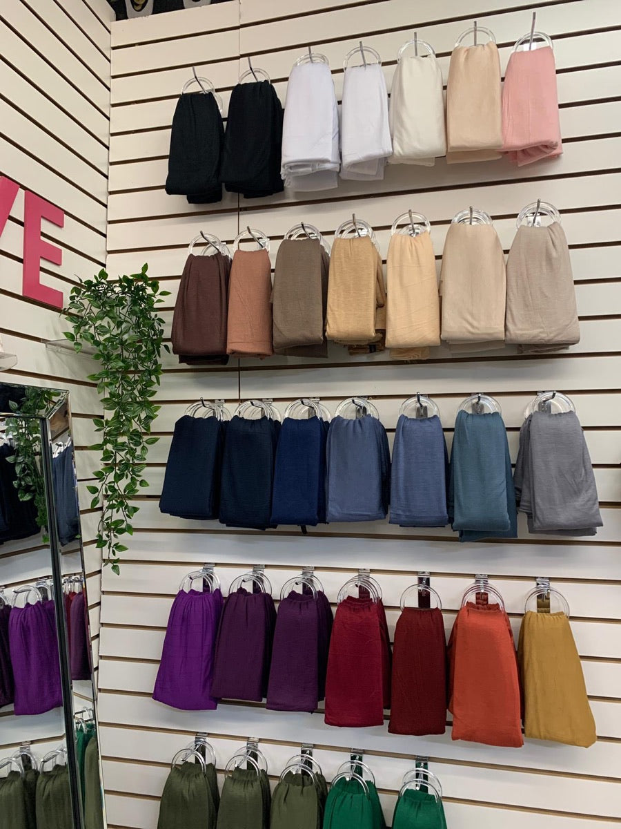 Neutral-toned hijabs arranged across the display wall at Nasiye